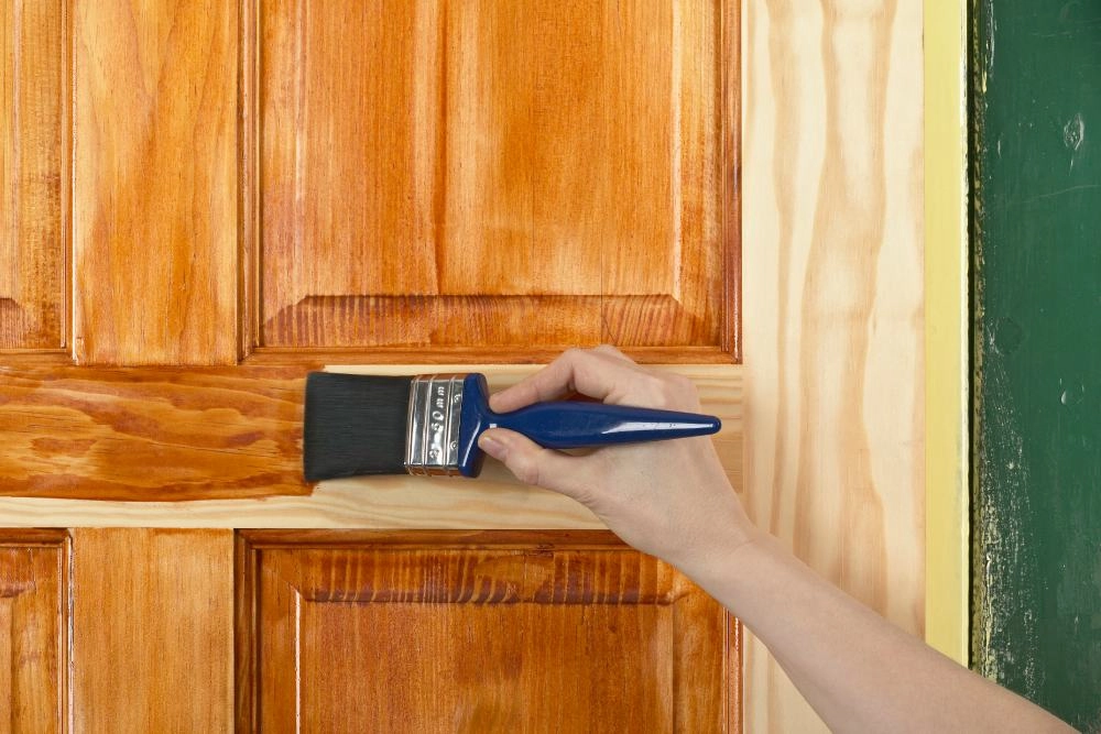 Holztür wird mit Pinsel lasiert.